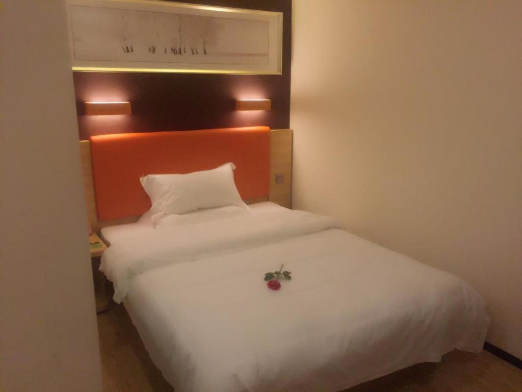 a bedroom with a white bed with a flower on it at 7Days Premium Yichang Gezhouba Branch in Yichang