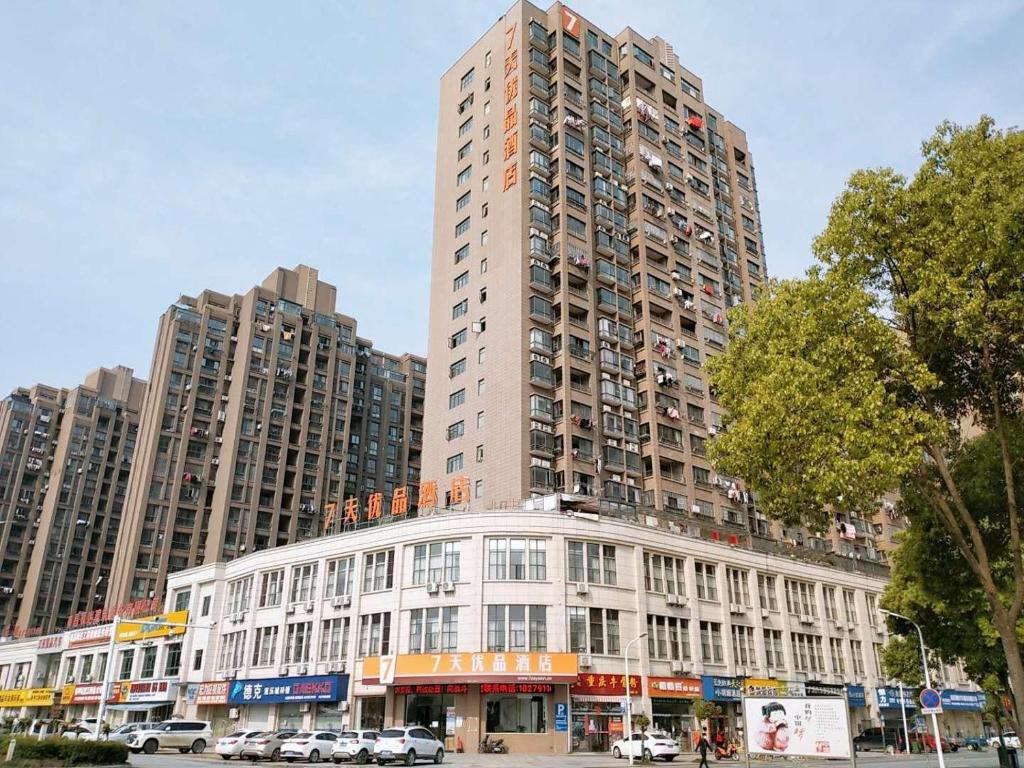 a tall building with cars parked in front of it at 7Days Premium Nanchang Liantang Yingbin Middle Avenue Xiaolan Industrial Park Branch in Nanchang