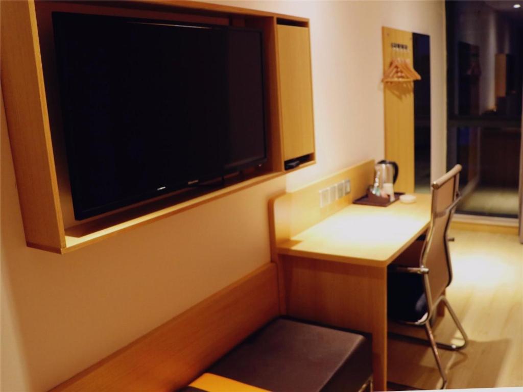 a room with a desk and a large flat screen tv at 7Days Premium Chengdu East Railway Station Subway Station Branch in Chengdu