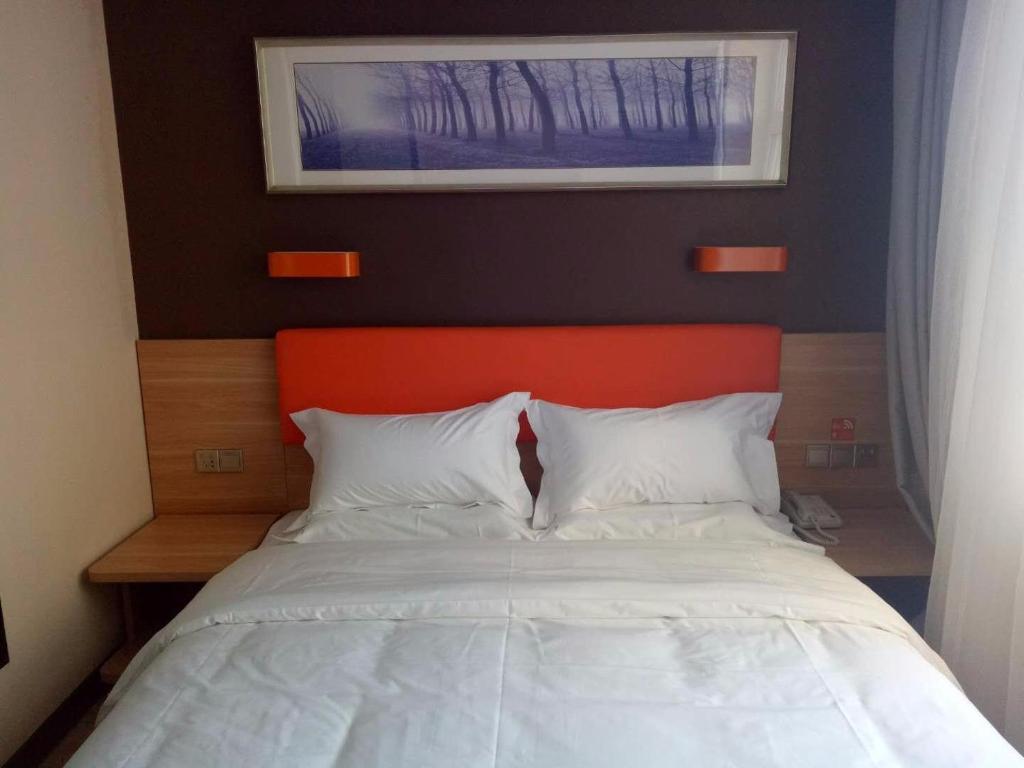a bed with an orange headboard and white pillows at 7Days Premium Heihe Nenjiang County Keyun Station Branch in Nenjiang
