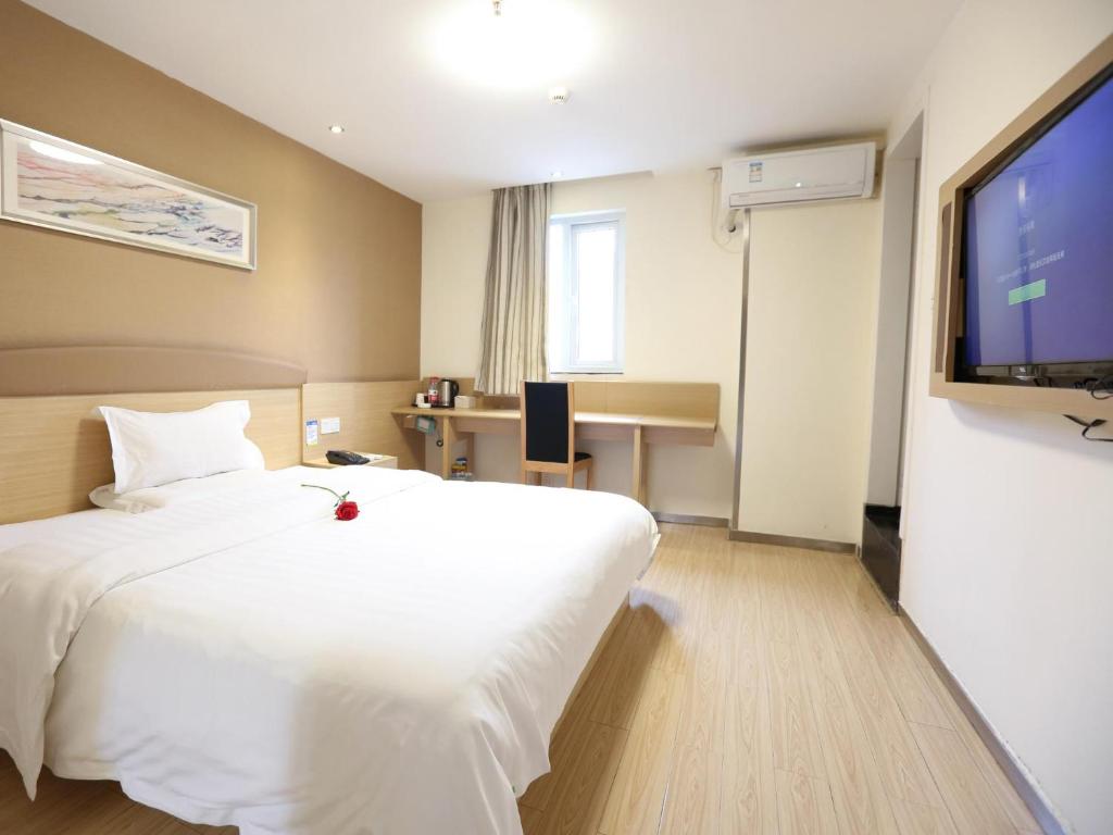 a hotel room with a white bed and a flat screen tv at 7Days Premium Changsha Hongxing South Bus Station Branch in Changsha