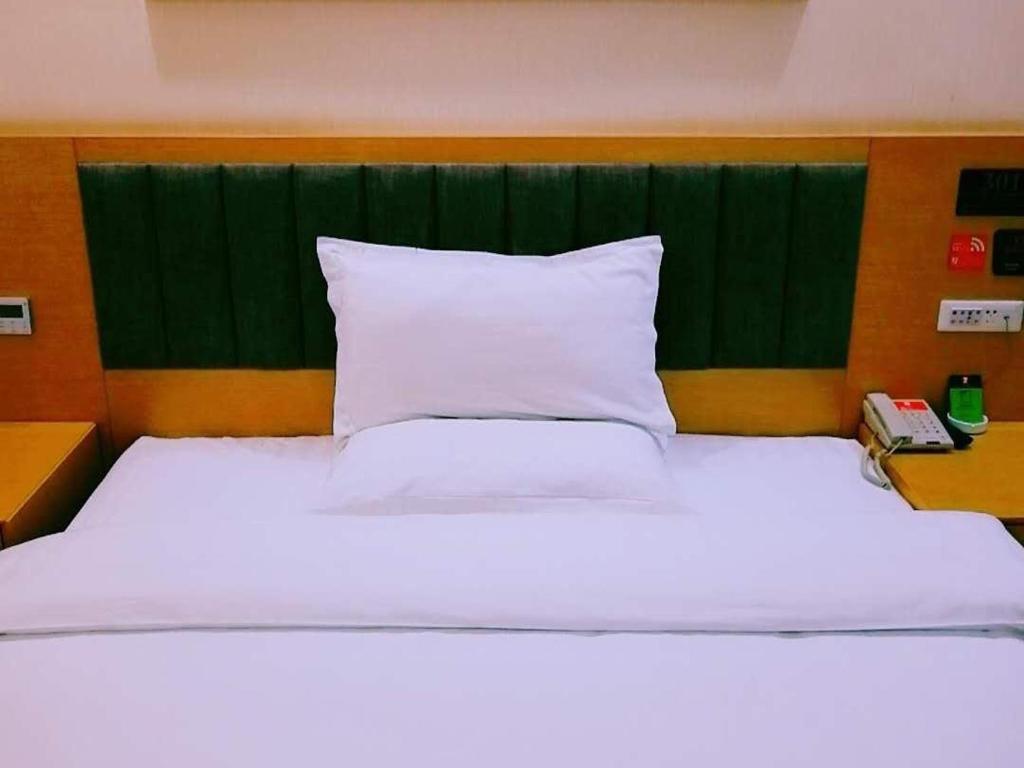 a bedroom with a large white bed with a green headboard at 7Days Premium Shiyan Renmin Road Sanyan Coach Station Branch in Shiyan