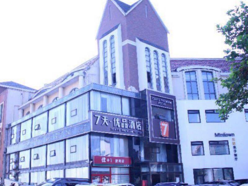 um edifício alto com um sinal em frente em 7Days Premium Qingdao Ocean World Haiyou Road Subway Station Branch em Qingdao