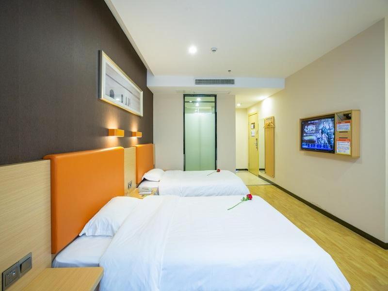 a hotel room with two beds and a tv at 7Days Premium Chongqing West Station Branch in Chongqing