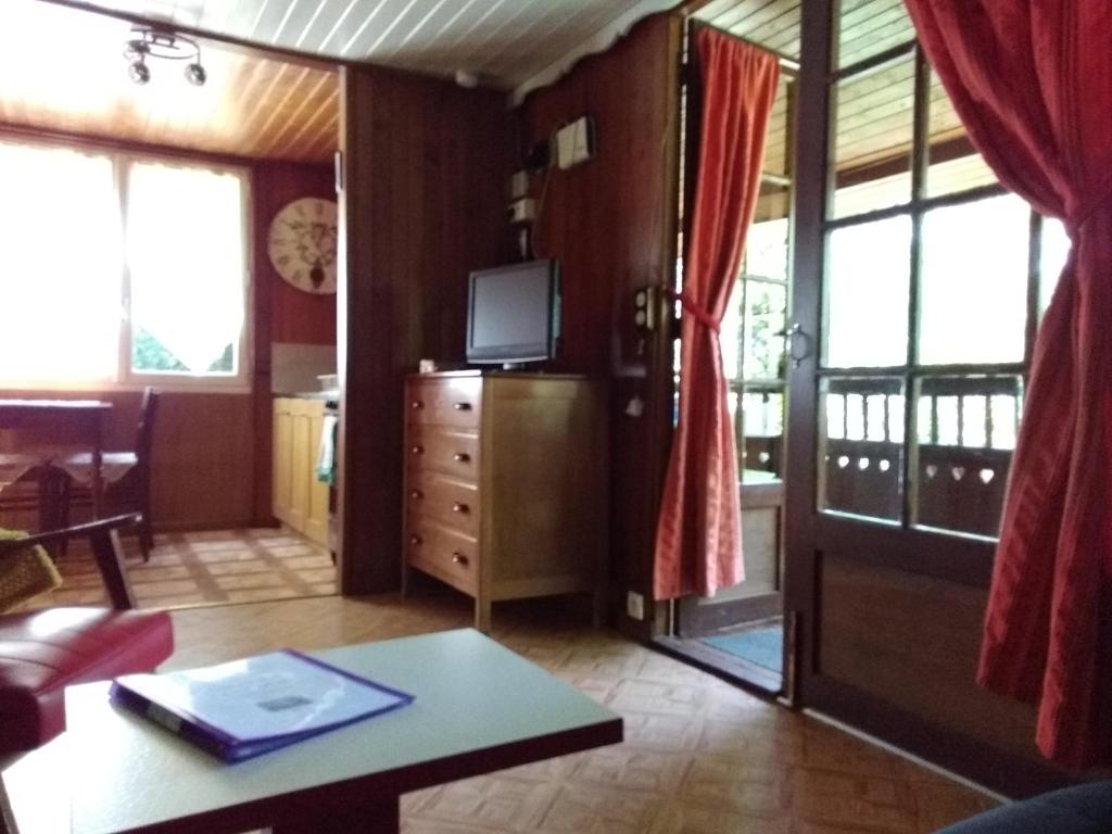 a living room with a television and a table at Chalet Vintage in Pollieu