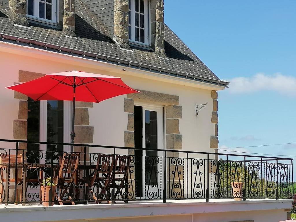 d'un balcon avec un parasol rouge et des chaises. dans l'établissement Propriété de charme-6 pers Le Pouldu, à Clohars-Carnoët