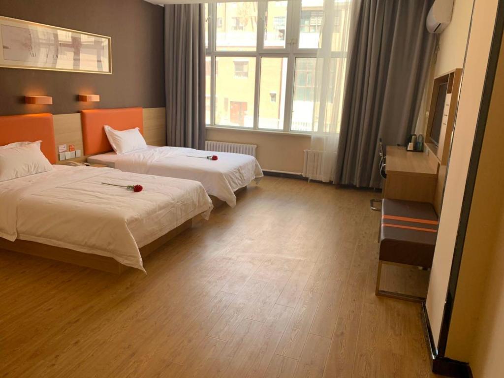 um quarto de hotel com duas camas com rosas vermelhas em 7Days Premium Bole Tuanjie South Road Lanhu Courtyard Branch em Dalt