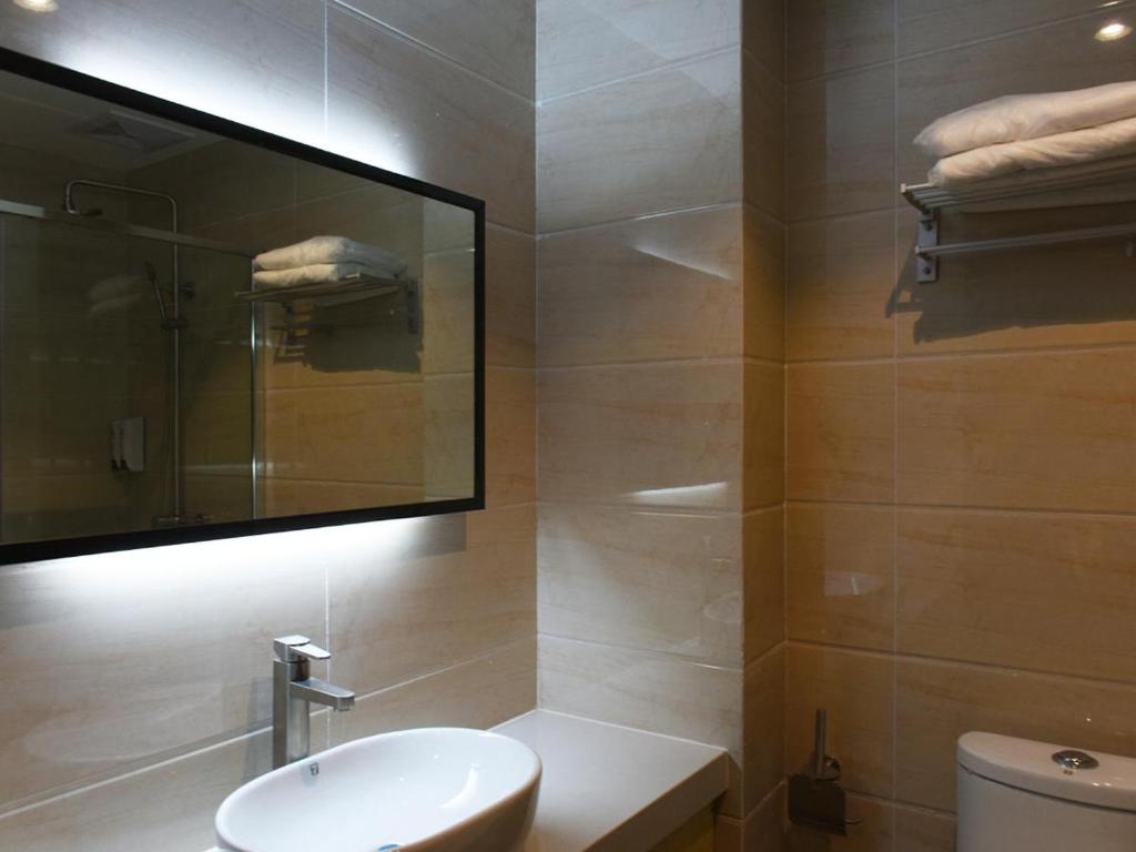 een badkamer met een wastafel, een spiegel en een toilet bij 7Days Premium Yantai Railway Station Branch in Yantai