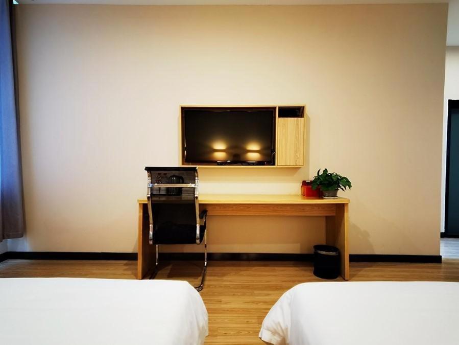 Habitación con 2 camas y escritorio con TV. en 7Days Premium Ordos City Government Branch, en Ordos