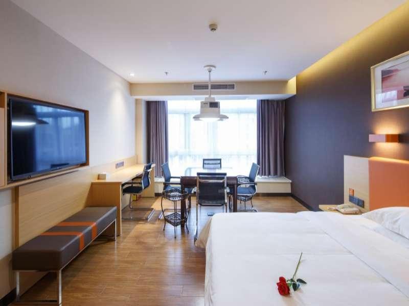a hotel room with two beds and a table and chairs at 7Days Premium Chongqing Liangping People's Square Center Branch in Liangping