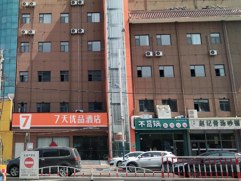 7Days Premium Hengshui Shenzhou City Government Branch في Hengshui: مبنى فيه سيارات تقف امامه