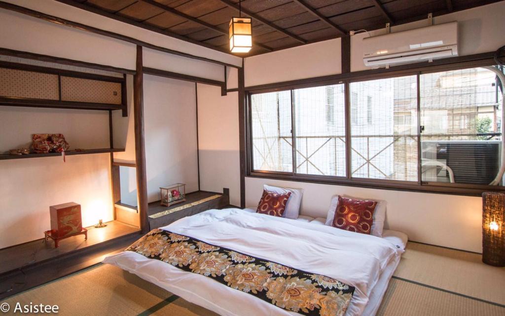 a bedroom with a bed and a large window at Sanjyomisasagi Umenotoan in Kyoto