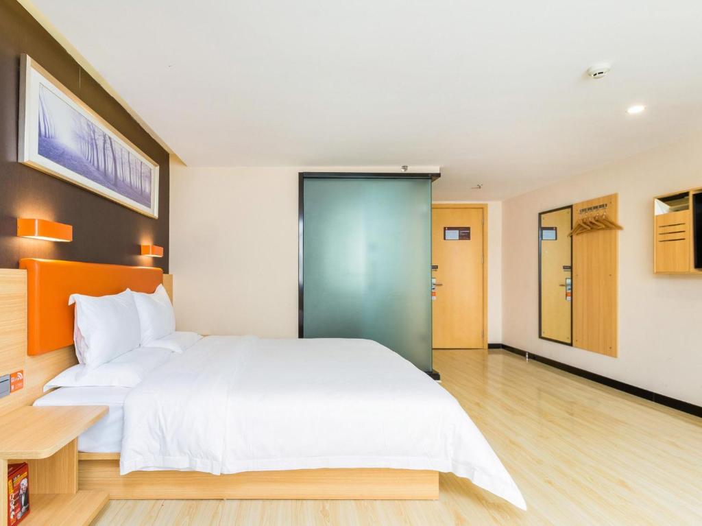 a bedroom with a white bed and a blue door at 7 Days Premium Sanya Bay Haiyue Plaza Foreign Trade Road Food Street Branch in Sanya