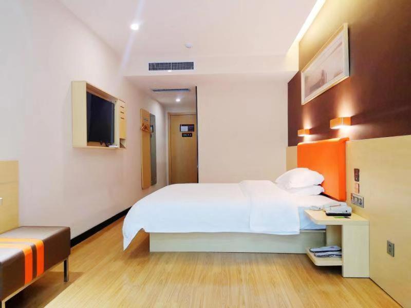 1 dormitorio con 1 cama blanca y TV en 7Days Premium Heze Train Station Branch, en Heze