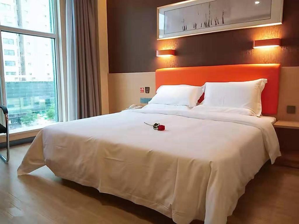 a bedroom with a large bed with a red rose on it at 7Days Premium Huaian Zhou Enlai Memorial Hall Yuanhuai East Road Branch in Hexia