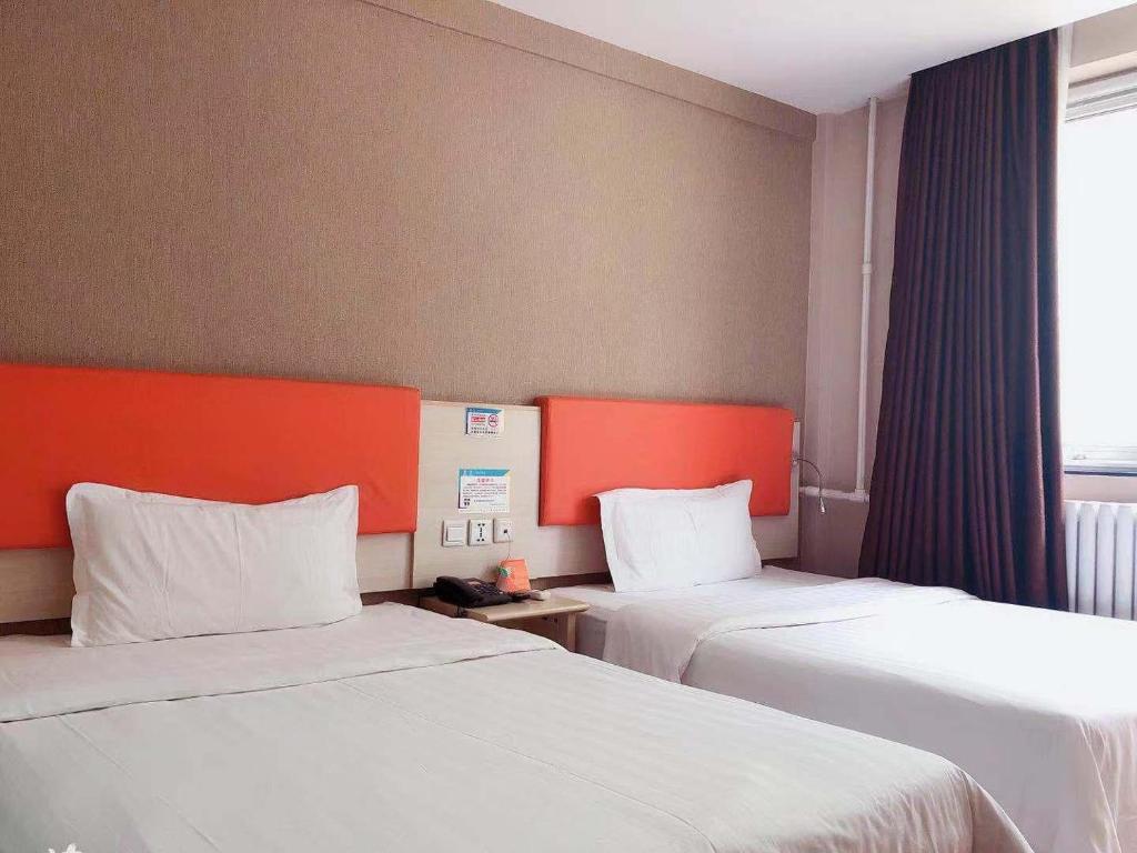 um quarto de hotel com duas camas e uma janela em 7Days Premium Beijing Zhongguancun Renmin University Suzhou Street Subway Station Branch em Pequim