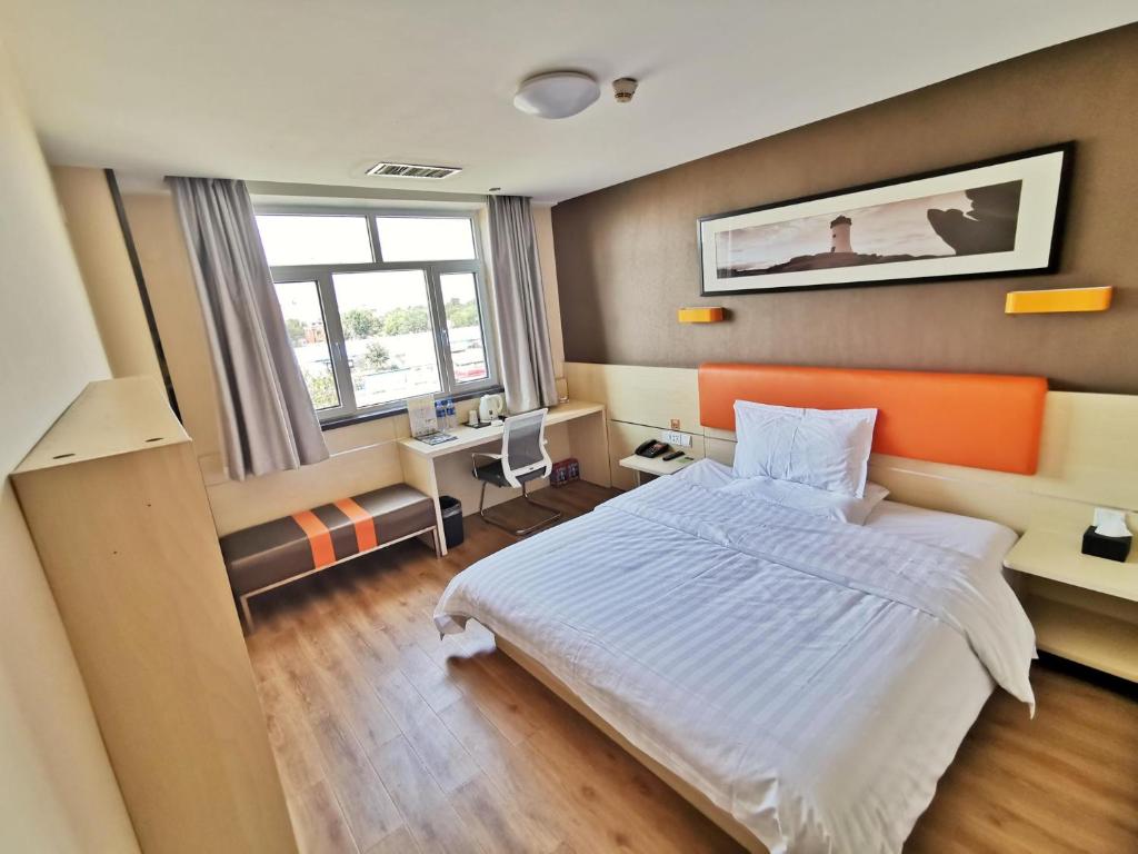 a bedroom with an orange and white bed and a window at 7Days Premium Tianjin Binhai International Airport Branch in Tianjin