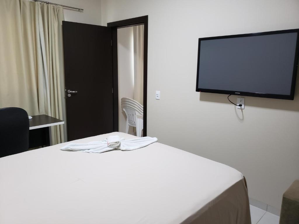 a hotel room with a bed with a flat screen tv at Flat Genoveva in Tangara da Serra