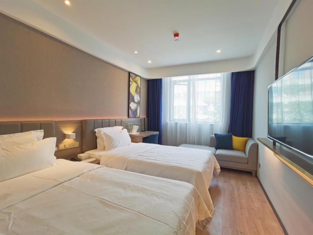 a hotel room with two beds and a flat screen tv at 7Days Premium Dongguan Fenggang Yongsheng Street Branch in Tiantangwei