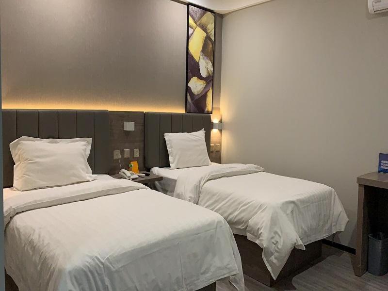 a hotel room with two beds with white sheets at 7Days Premium Beijing South Railway Station Jiaomen East Subway Station Branch in Beijing