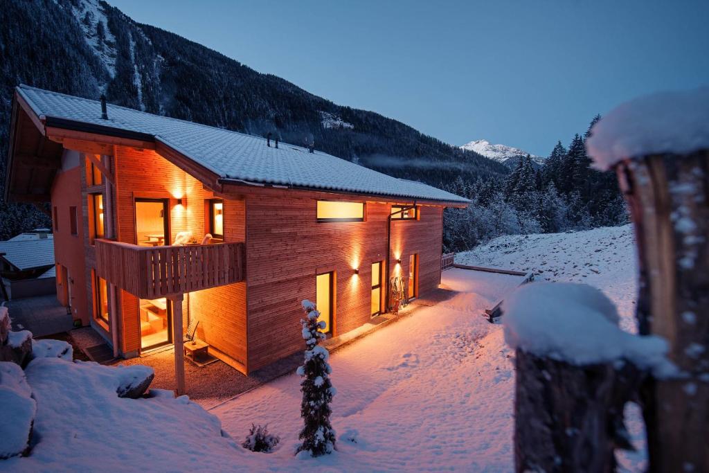 una cabaña de madera en la nieve con luces encendidas en Ferienhaus zum Stubaier Gletscher - WALD, en Neustift im Stubaital