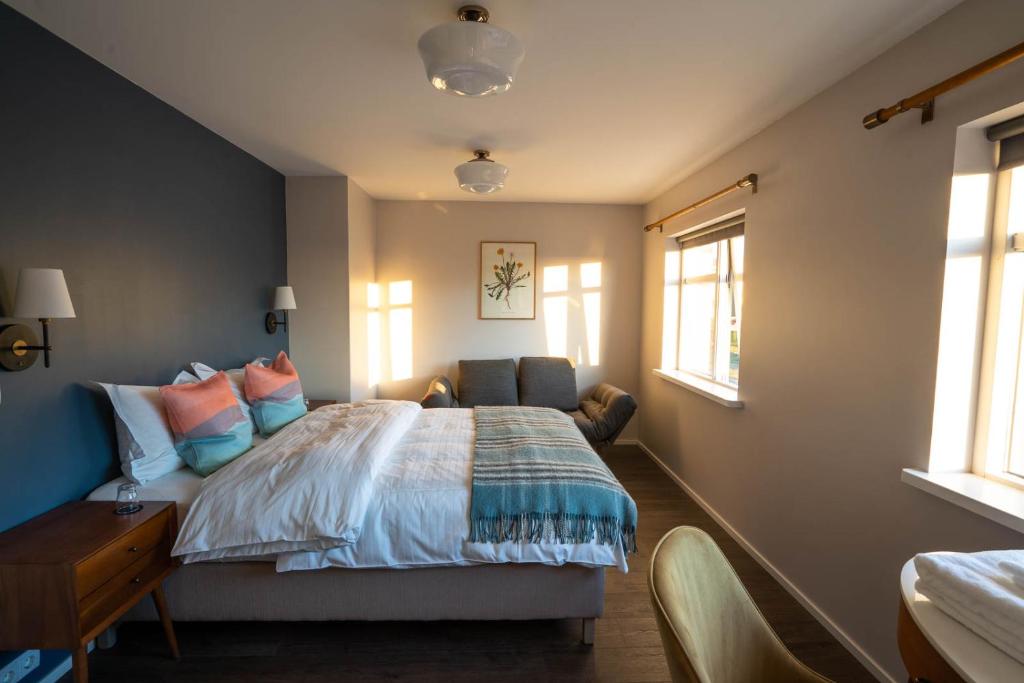 een slaapkamer met een bed, een bureau en ramen bij Soti Lodge in Fljot