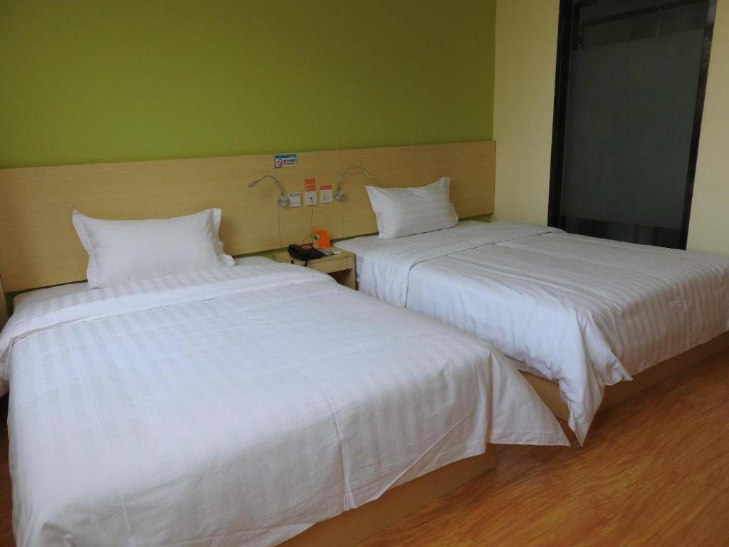 two beds sitting next to each other in a room at 7 Days Inn Wuhan Jiangxia Century Plaza Branch in Wuhan