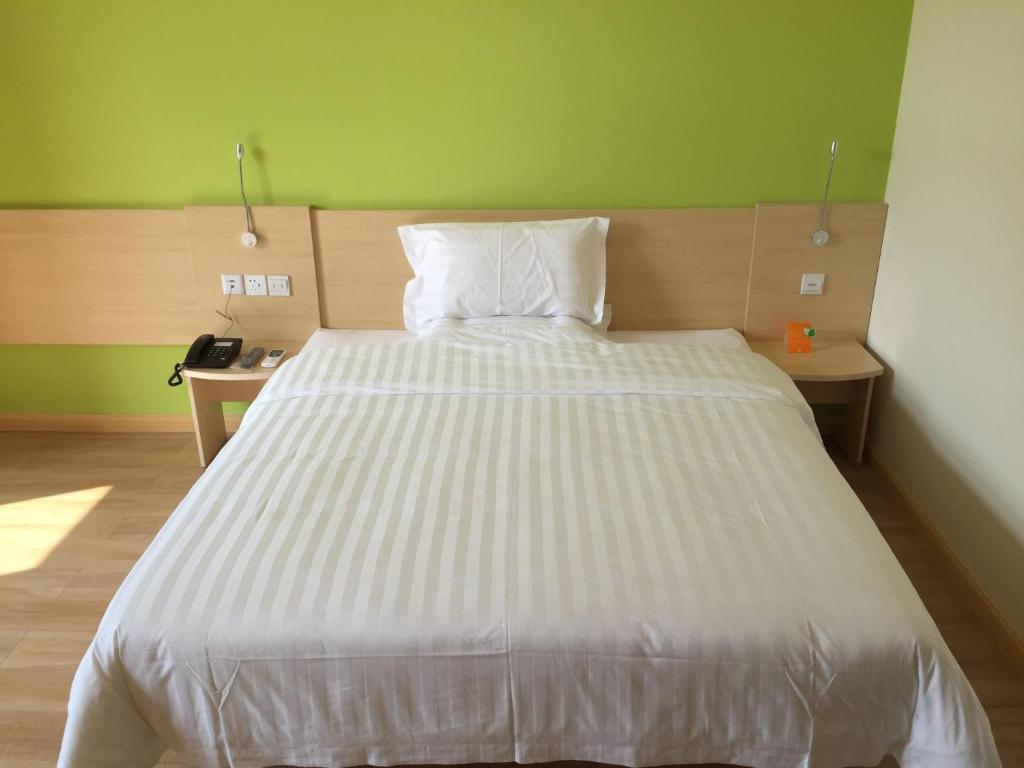 duże białe łóżko w pokoju z zieloną ścianą w obiekcie 7Days Inn Xiangfen Dingtao Hypermarket Store Branch w mieście Linfen