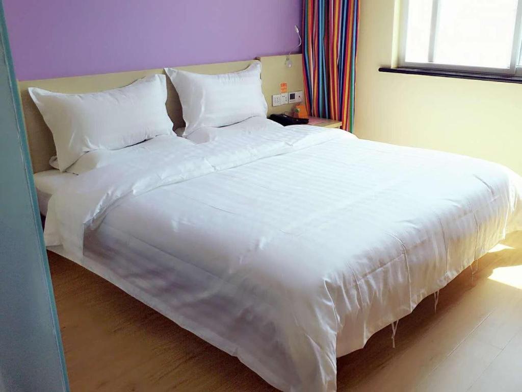 1 cama blanca grande con sábanas y almohadas blancas en 7Days Inn Hanzhong Yang County Heping Road Branch, en Hanzhong
