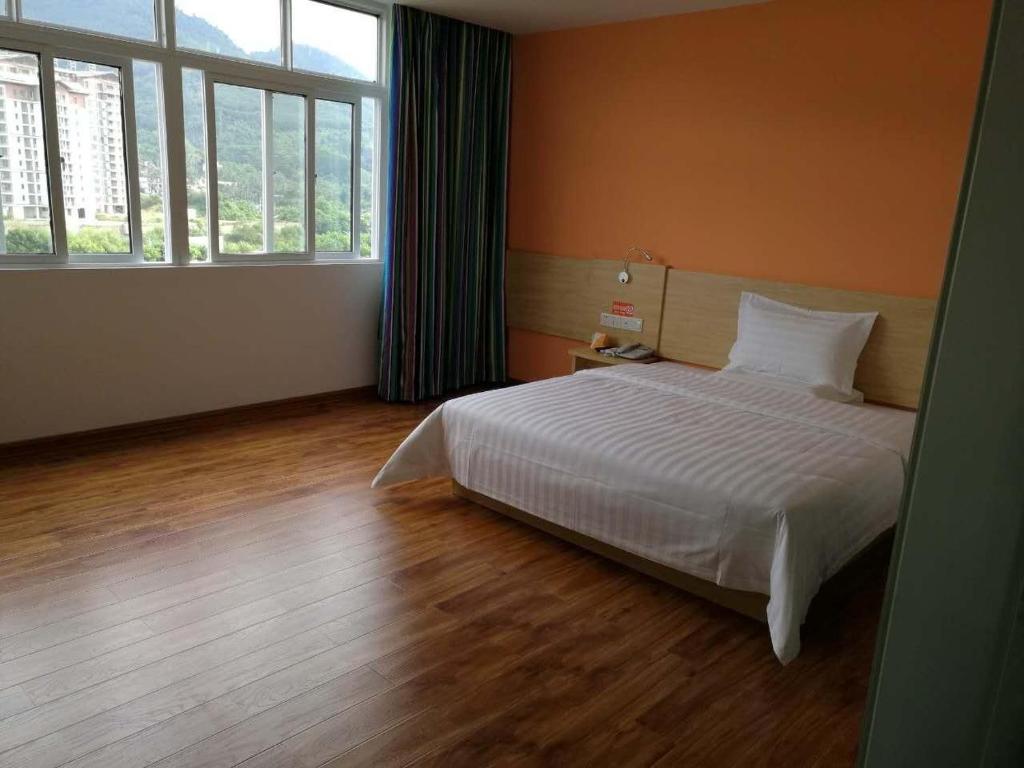 a bedroom with a white bed and a large window at 7 Days Inn Wuzhishan Yanhe South Road Branch in T'ung-shih-shih