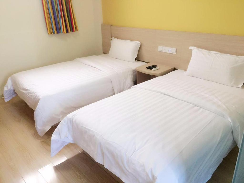 two beds in a hotel room with white sheets at 7Days Inn Nanjing Gulou Yunnan Road Metro Station Branch in Nanjing