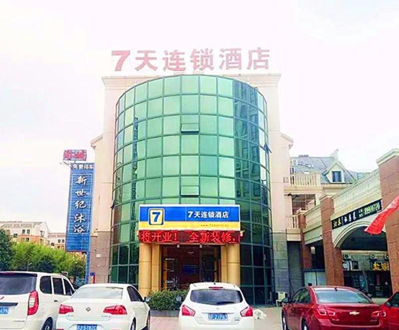 7Days Inn Yancheng Yingbin Avenue Engineering College Branch في يانتشنغ: مبنى فيه سيارات تقف امامه