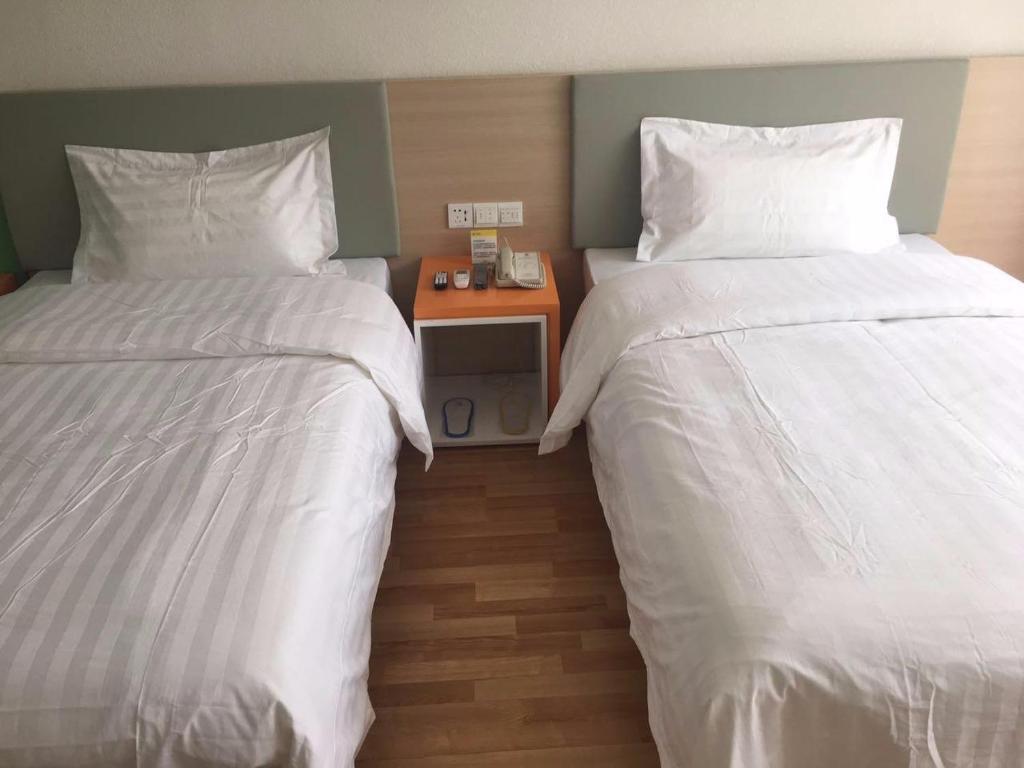 2 bedden in een hotelkamer met witte lakens bij 7 Days Inn Zhangjiakou Huailai Shacheng Branch in Gujiayao