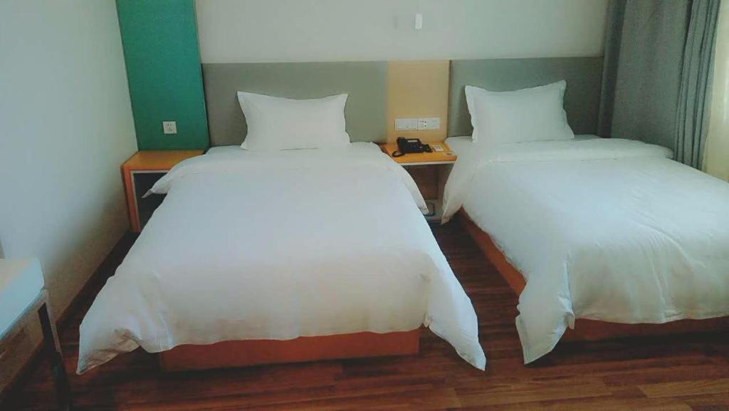 two beds sitting next to each other in a room at 7Days Inn Urumqi Midong Middle Road Shenhua Mining Bureau Branch in Ürümqi