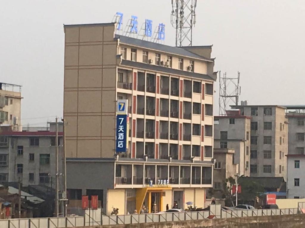 Un edificio alto con una señal azul. en 7Days Inn Ganzhou Huichang Changshou Branch, 