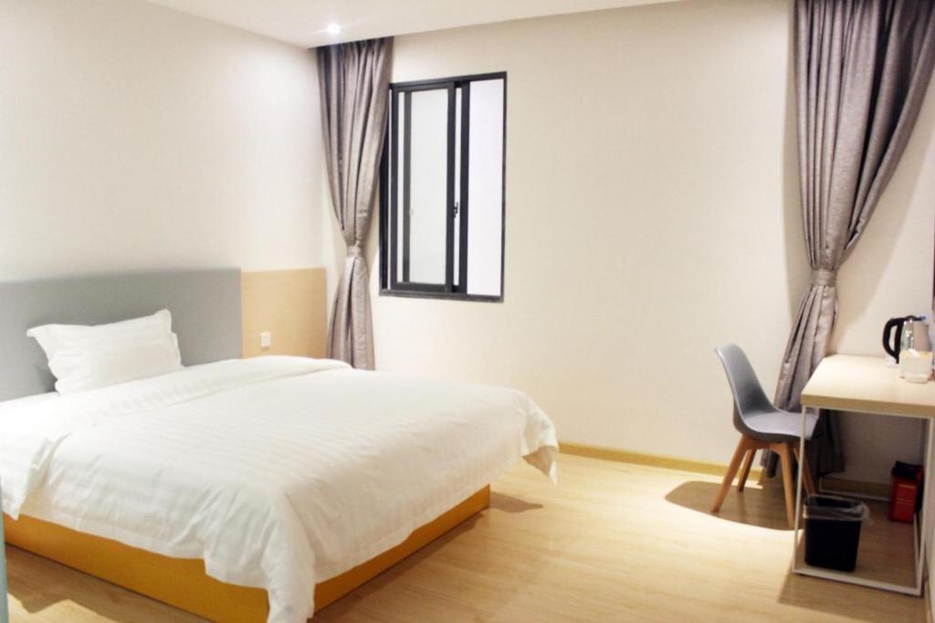 a bedroom with a bed and a desk and a window at 7Days Inn Chongqing Longtou Temple North Train Station North Plaza Branch in Chongqing