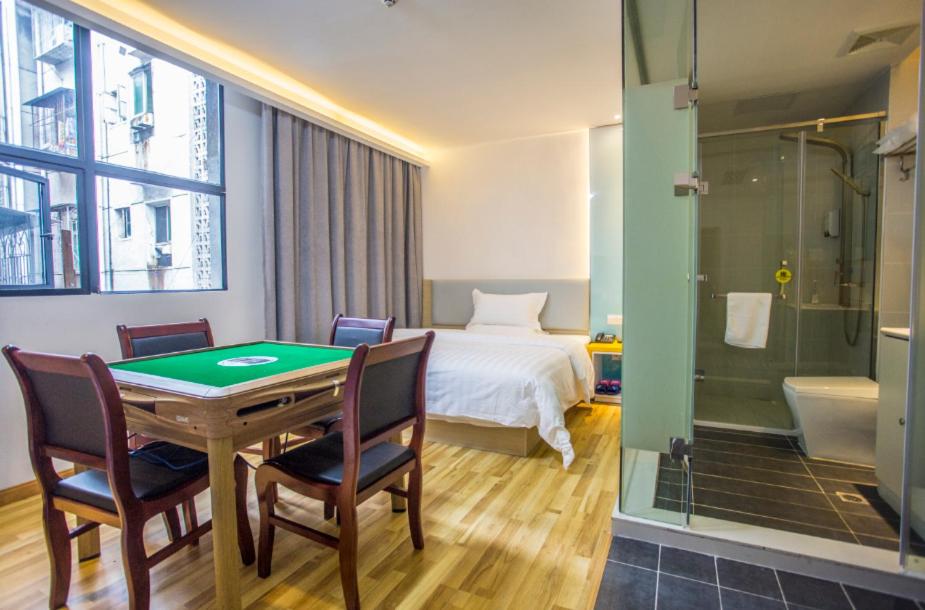 a room with a table and chairs and a bedroom at 7Days Inn Huaihua Zhijiang Pedestrian Street Branch in Huaihua