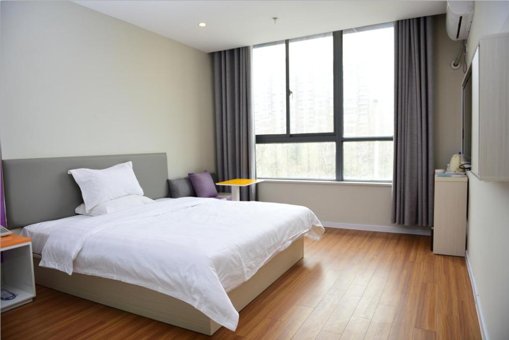 a bedroom with a white bed and a large window at 7Days Inn Xuzhou Xincheng City Council Aoti Branch in Xuzhou