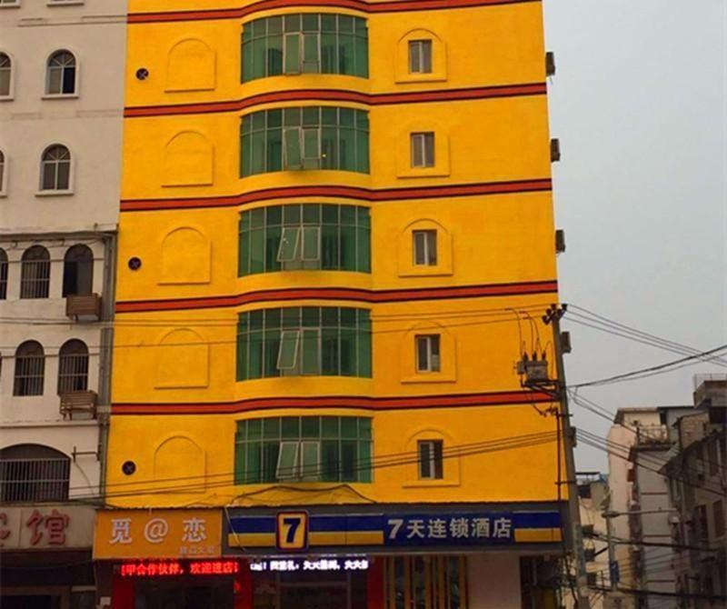 un bâtiment jaune avec des fenêtres vertes dans une ville dans l'établissement 7Days Inn Nanning Jiangnan Bus Station Subway Exit Branch, à Nanning