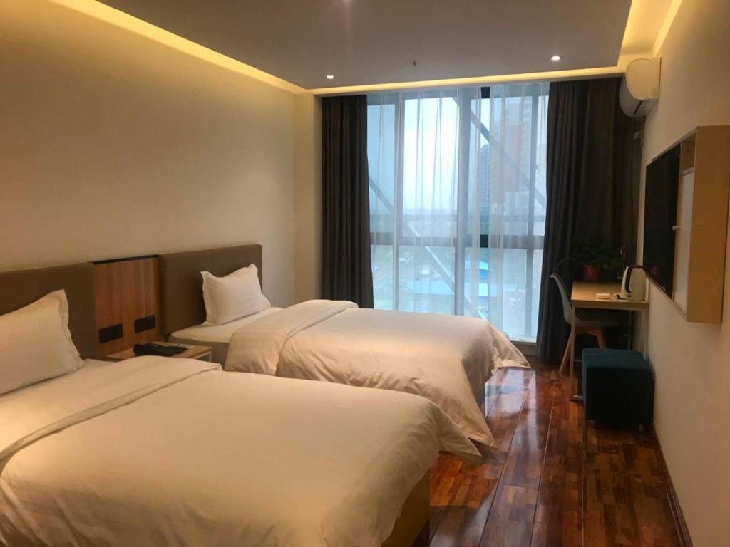 a hotel room with two beds and a window at 7Days Inn Xianyang Xingping Jincheng Road Branch in Xianyang