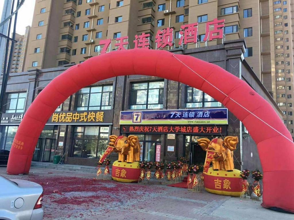 un grande arco rosso di fronte a un edificio di 7Days Inn Hulu Island Xingcheng University Town Branch a Huludao