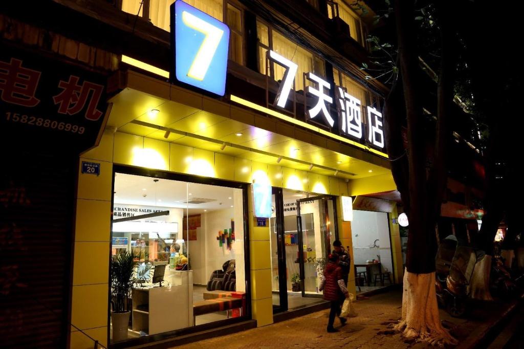 een vrouw die 's nachts buiten een winkel loopt bij 7Days Inn Neijiang Longchang Xinhua Street Branch in Neijiang