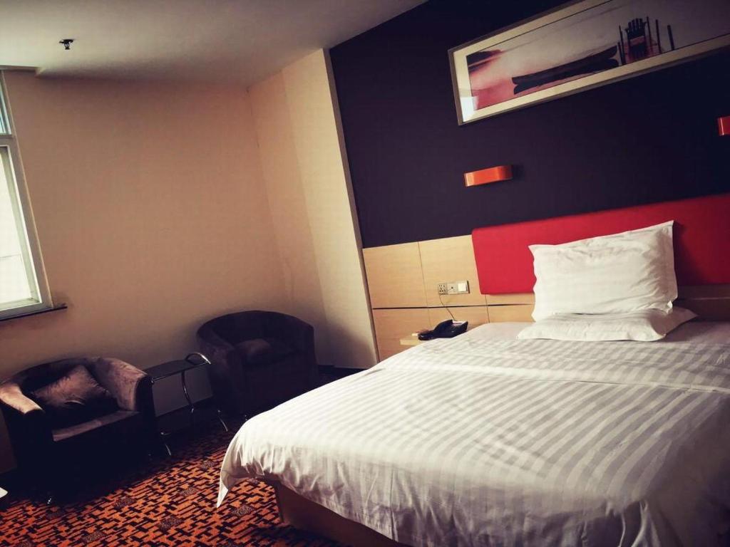 een hotelkamer met een bed en een stoel bij 7Days Inn Binzhou Wudi Central Street Branch in Binzhou