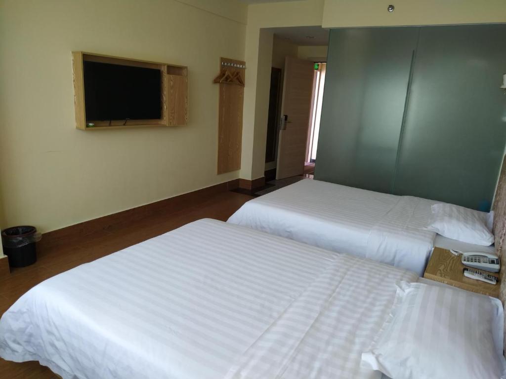 two beds in a hotel room with a tv at 7Days Inn Sanya Yalong Bay Branch in Sanya