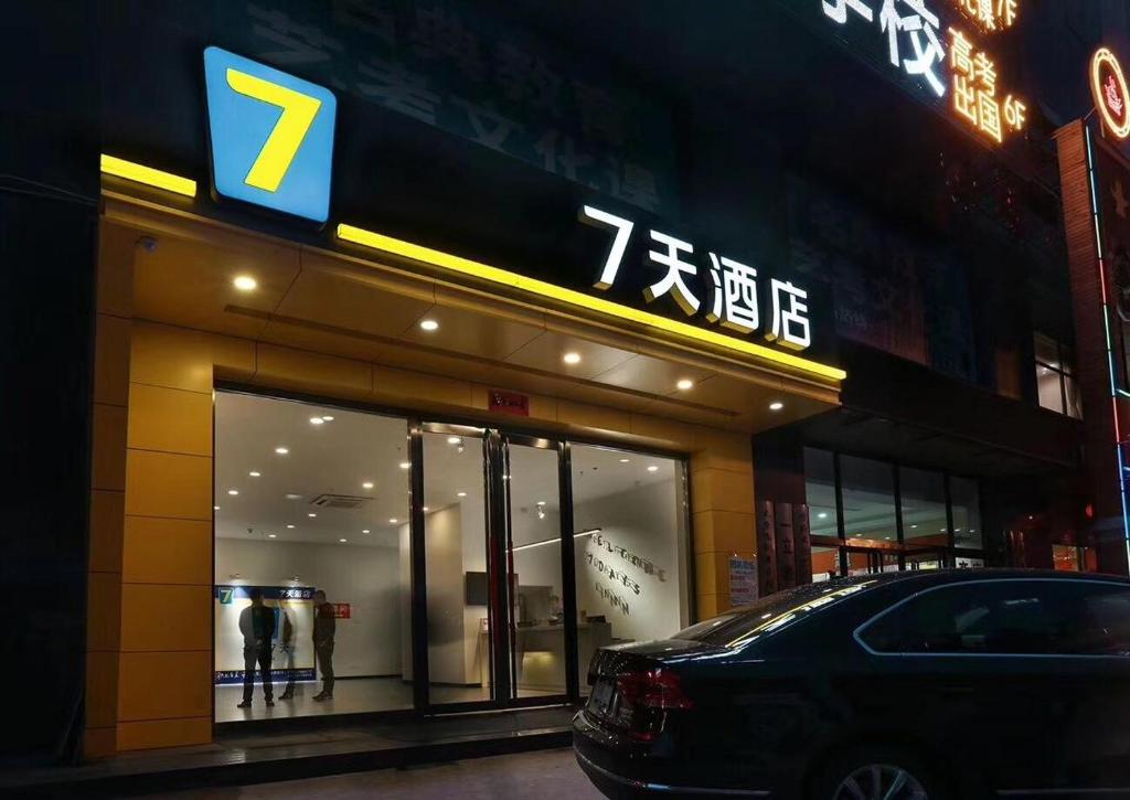 7Days Inn Taiyuan South Railway Station Branch في تاييوان: محل فيه سيارة متوقفة أمامه