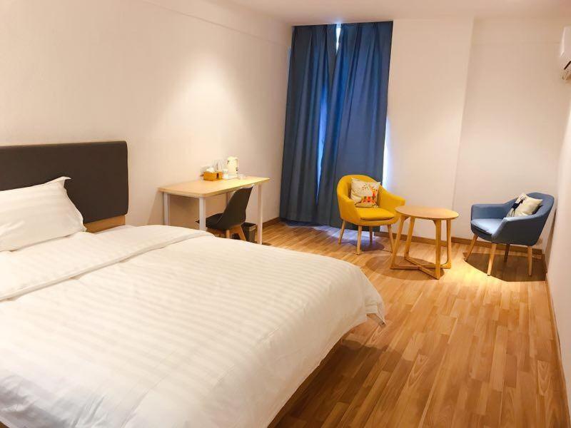 a bedroom with a bed and two chairs and a table at 7 Days Inn Nanchang Qingshanhu Avenue Minfeng Road Branch in Nanchang