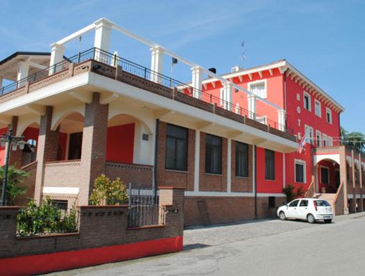 un coche blanco estacionado frente a un edificio rojo en Hotel Cigno Reale, en Rolo