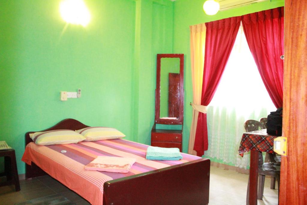 a bedroom with a bed with green walls and a window at Wijaya Tourist INN in Warakapola