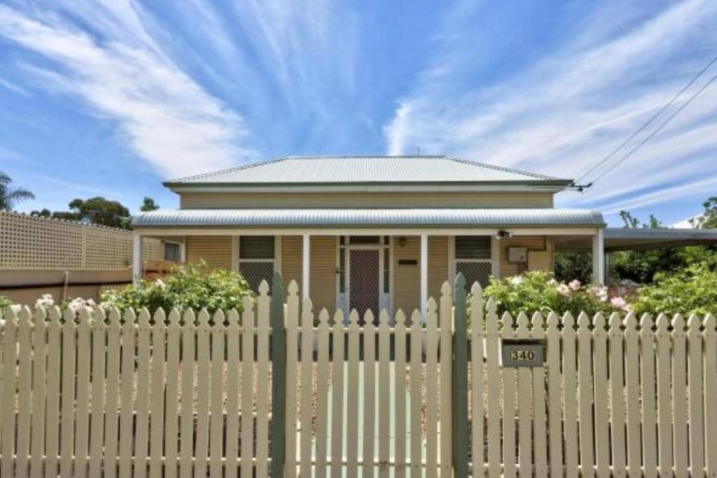 a house behind a picket fence with a white picket fenceasteryasteryastery at Maeville Cottage in Broken Hill
