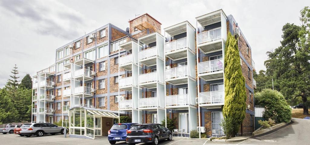 un edificio de apartamentos con coches estacionados frente a él en Adina Place Motel Apartments, en Launceston